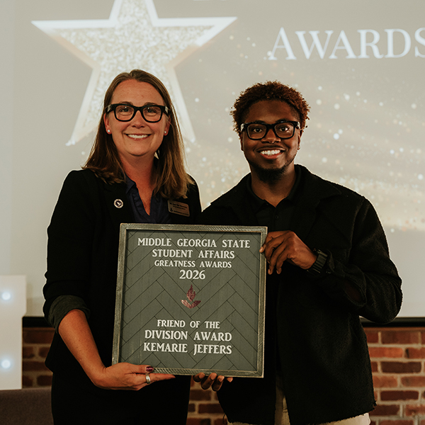 Dr. Jennifer Brannon and award recipient Dr. Kemarie Jeffers smile while holding a plaque that reads, "Middle Georgia State Student Affairs Greatness Awards 2026 - Friend of the Division Award, Kemarie Jeffers."